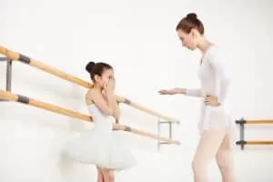 the teacher was saying a word to a dancer while the dancer covering her mouth at the dance studio