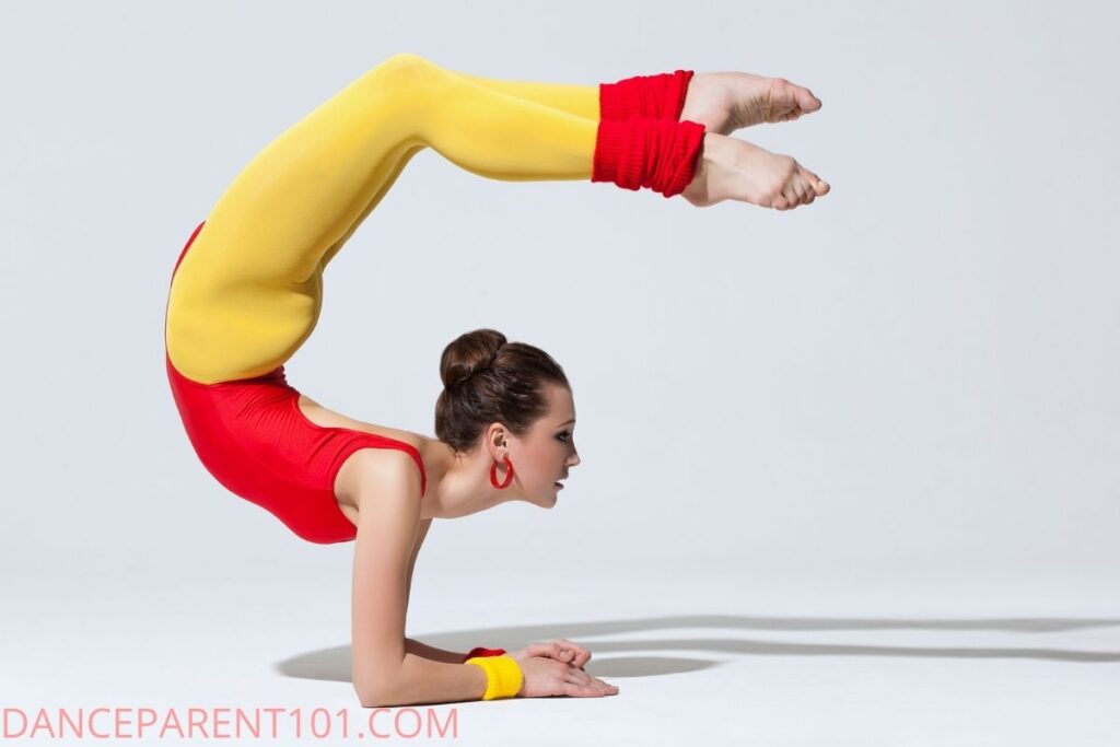 girl in elbow stand with legs over head wearing red and yellow costume