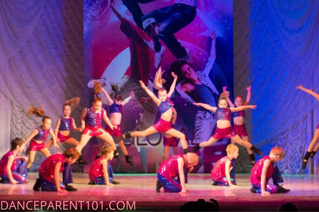 Group of young dancers on the stage at a competition in pink and purple costumes