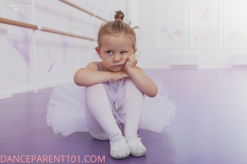 Little ballet dancer in a tutu with hand to chin looking bored
