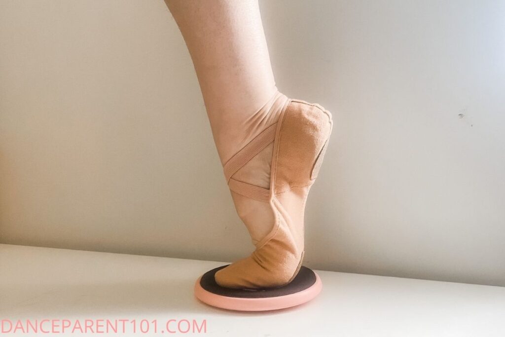 Foot in releve in a ballet shoe on a turn disc