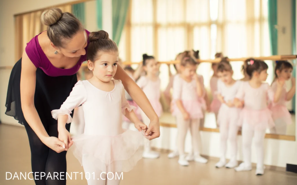 Image of young girl in a ballet class with teacher helping her - What To Expect From Your Child's First Classical Ballet Classes