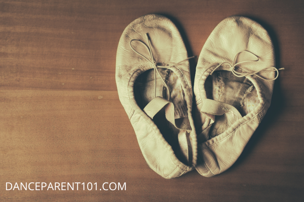 An old pair of ballet shoes on a brown wooden background