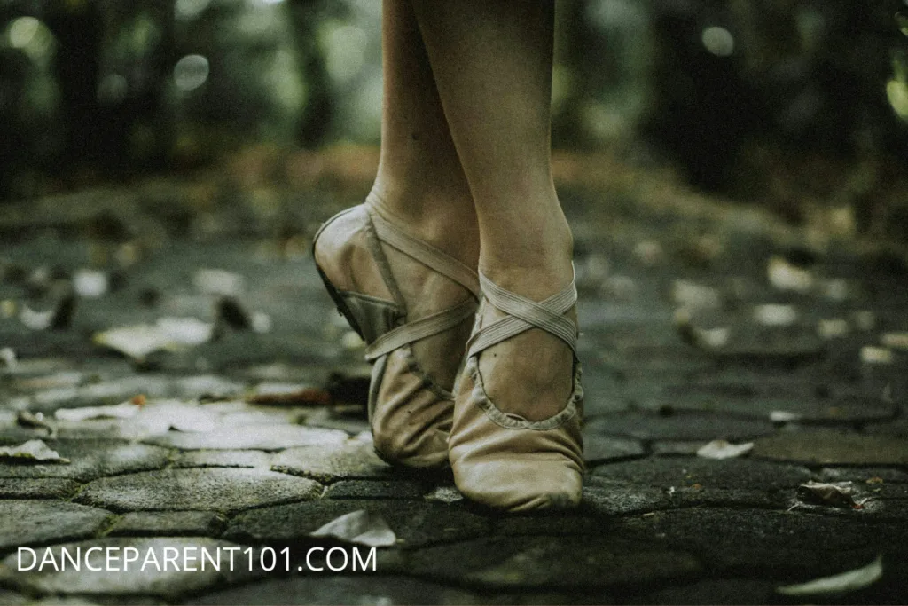 Ballet dancer's feet wearing dirty ballet shoes on a sidewalk