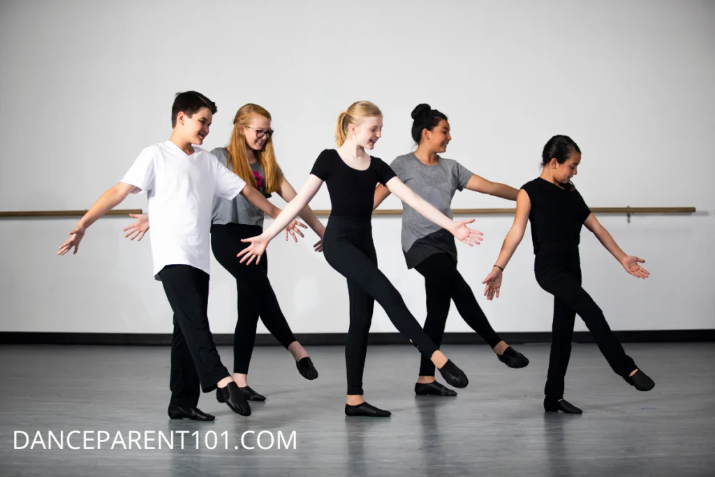 A group of 5 young dancers pose in a dance studio, wearing black and gray outfits