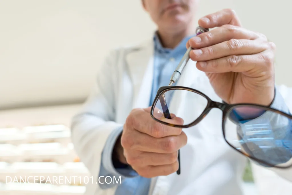 An image of an eye doctor in a white coat using a small screwdriver to fix a pair of glasses