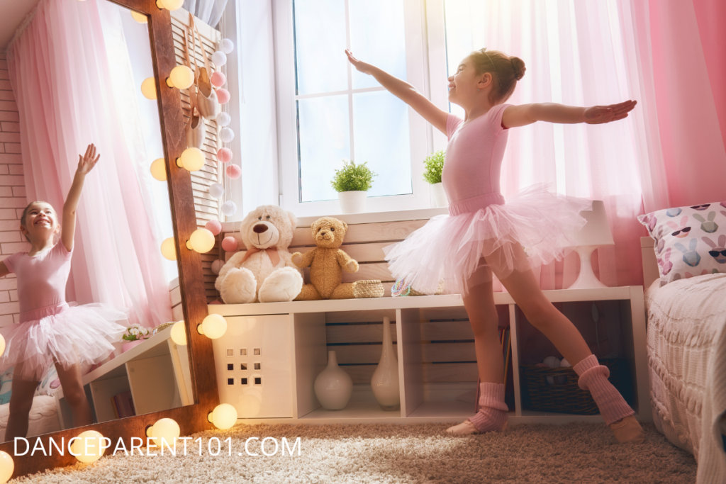 A young girl wearing a pink leotard and tutu practices ballet in her bedroom