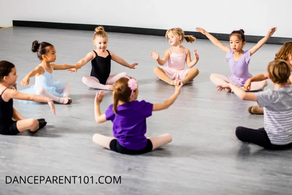 Children sitting in a circle in a dance studio.