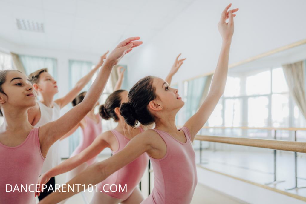 Image of young ballet dancers wearing pink leotards in a dance studio. They are close together in a ballet pose.